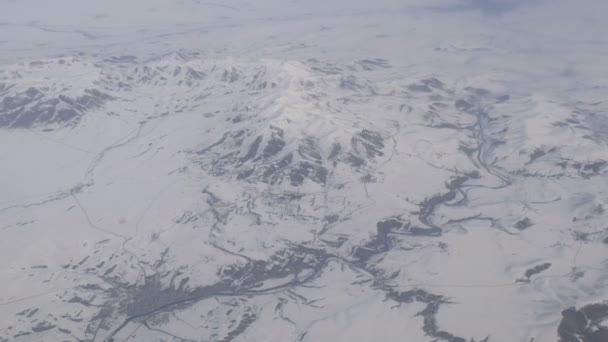 うっすら雪、雲、通り過ぎる飛行機の窓からの眺めと美しい山の範囲 — ストック動画