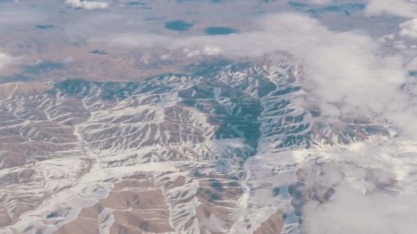 Εκπληκτική ομορφιά της οροσειράς, ελαφρώς καλυμμένη με χιόνι, περνώντας από τα σύννεφα, μια θέα από το παράθυρο του αεροπλάνου — Αρχείο Βίντεο