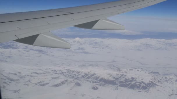 Oszałamiające piękno gór, lekko pokryte śniegiem, przechodzi przez chmury, widok z okna samolotu — Wideo stockowe