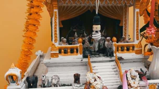 Beautifully decorated traditional Buddhist altar in the garden in Thailand, with flowers and various symbolic figures — Stock Video