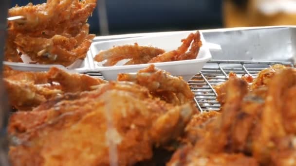 Street food of Thailand. Fried chicken pieces in batter.The seller on the street is selling an exotic dish. The buyer selects a piece of meat with the help of special tongs for food — Stock Video