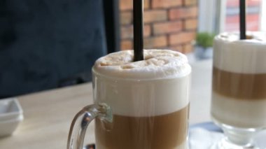 Şık kafe tablo şeffaf özel bardakta süt ve hava köpük ve siyah bir saman ile kahve latte standları