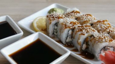 Büyük rulo suşi Japon mutfağı yalan üzerine şık bir Restoran, bir sos kase soya sosu, wasabi, zencefil ve limon dilim için yanında bir tabloda üzerinden