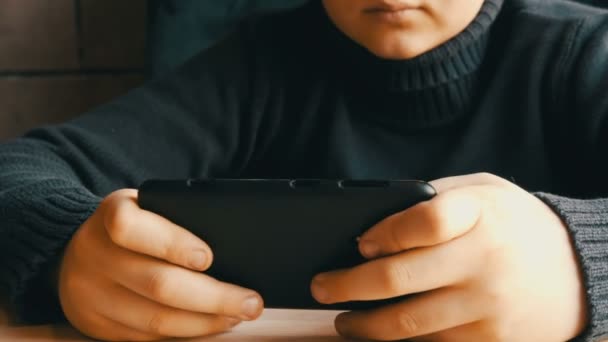 Manos de niño adolescente jugando en el teléfono inteligente negro en un elegante café — Vídeos de Stock