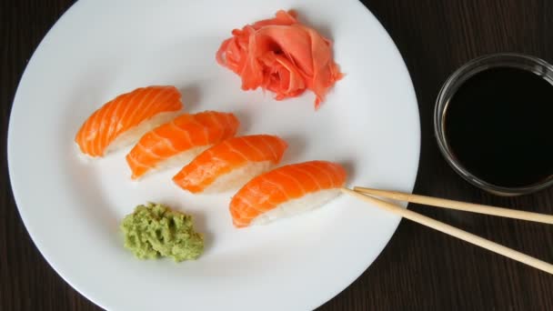 Vier große Sushi mit Lachsstücken liegen auf einem großen flachen Teller. Kamera bewegt sich nach rechts — Stockvideo