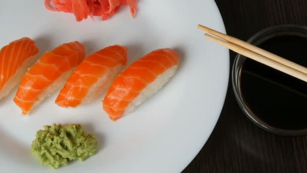 Four large sushi with piece of salmon lie on a large flat plate. Camera moves right — Stock Video