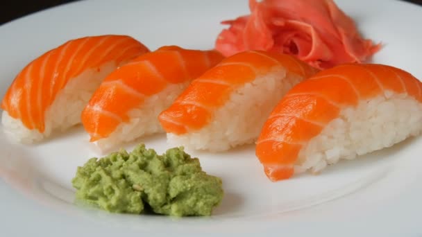 Cuatro grandes sushi con trozo de salmón se encuentran en un plato plano grande . — Vídeos de Stock