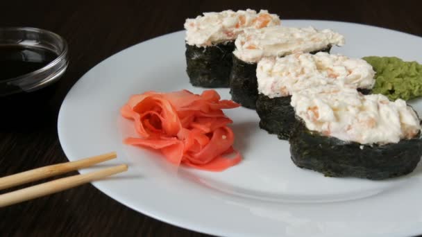 Un gran plato blanco en el que se encuentra cuatro enormes nigiri sushi junto al jengibre rosa y wasabi verde — Vídeo de stock