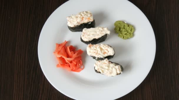 Un gran plato blanco en el que se encuentra cuatro enormes nigiri sushi junto al jengibre rosa y wasabi verde — Vídeos de Stock