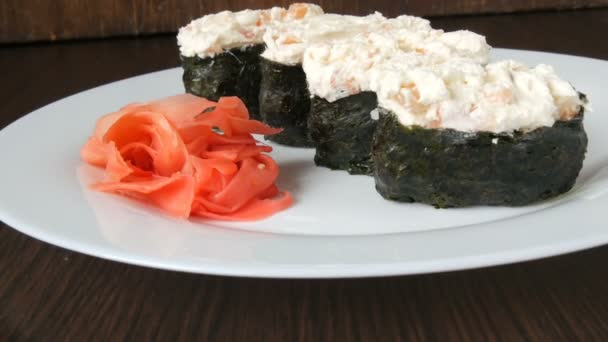 Un gran plato blanco en el que se encuentra cuatro enormes nigiri sushi junto al jengibre rosa y wasabi verde — Vídeo de stock