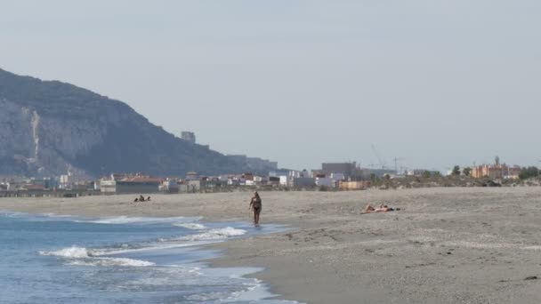 Pareja joven camina a lo largo de las orillas del Mar Mediterráneo sobre el fondo del Peñón de Gibraltar, envuelto en aire caliente de levadura — Vídeos de Stock