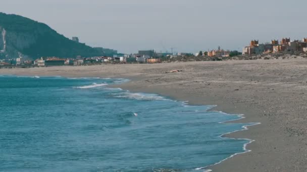 Mar Mediterráneo en sus hermosas olas, golpeando contra la arena blanca y el Peñón de Gibraltar contra el fondo — Vídeos de Stock