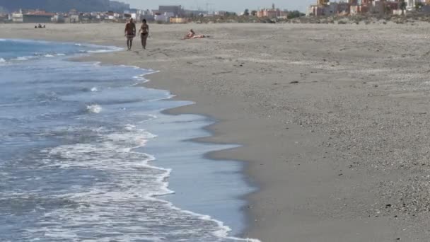 Young couple walks along the shores of the Mediterranean Sea against the background of the Rock of Gibraltar, enveloped in hot yeast air — Stock Video