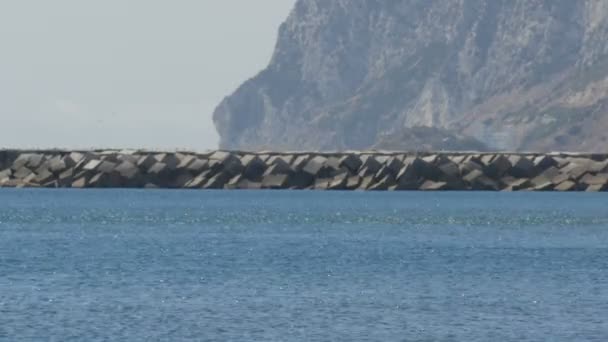 Muelle de piedra en el Mar Mediterráneo, el Estrecho de Gibraltar sobre un fondo del Peñón de Gibraltar y el temblor del aire caliente — Vídeo de stock
