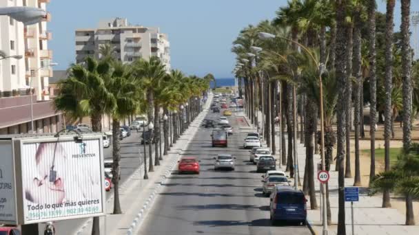 26. september - 2017, la linea, spanien: autos fahren die straße entlang zu einer seite, an der hohe grüne palmen wachsen — Stockvideo