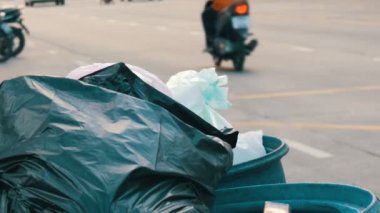 Plastik torbalar artık yemek yiyecek ve diğer atık hangi otomobil ve Motosiklet sürücü üzerinde yoğun bir cadde üzerinde ile tam tıkalı çöp kovası