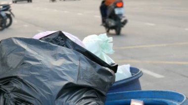 Plastik torbalar artık yemek yiyecek ve diğer atık hangi otomobil ve Motosiklet sürücü üzerinde yoğun bir cadde üzerinde ile tam tıkalı çöp kovası