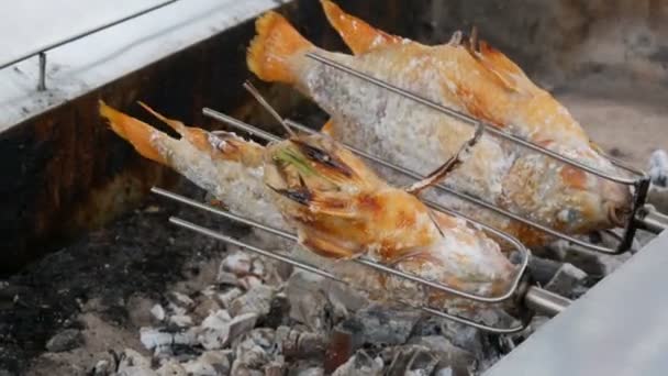 Εθνικό πιάτο ταϊλανδικά, τηγανητά ψάρια στην σούβλα στο αλάτι και με χόρτα. Εξωτικά τρόφιμα της Ταϊλάνδης και της Ασίας — Αρχείο Βίντεο