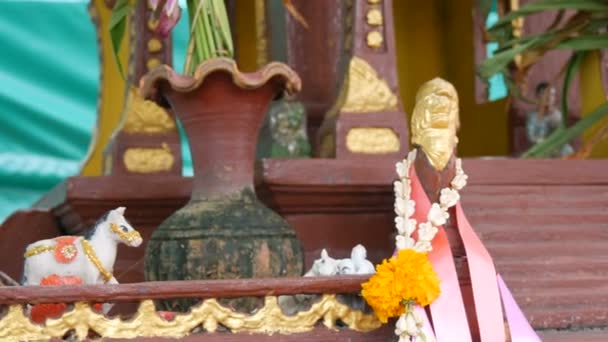 Brown Buddhist small altar for prayers in a garden, decorated with flowers and various statuettes — Stock Video