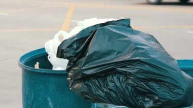 Yaşlı bir kadın dışarı bir dolu paket-in çöp tenekesi çöpe atar