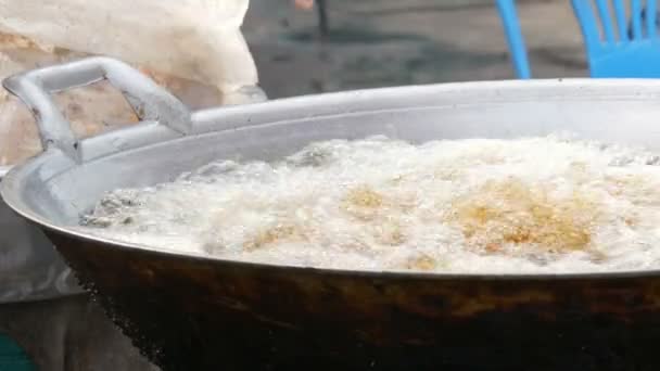 Comida callejera en Tailandia y Asia. Gran cuba hirviendo en la que las mujeres cocinan a mano y ponen trozos de pollo. Pollo en forúnculos empanados en una cacerola grande — Vídeos de Stock