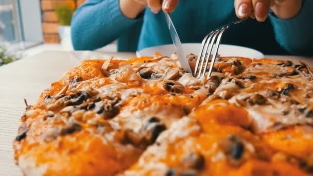 Een vrouw snijdt en zet een stuk pizza op een plaat. Een enorme versgebakken Italiaanse pizza met kip maïs van champignons en kaas op de tafel in een restaurant — Stockvideo