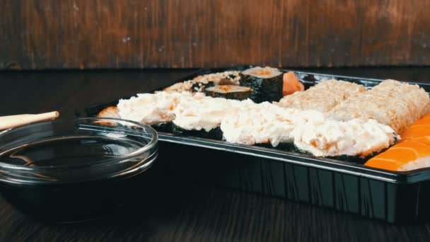 Câmera zooms. Grande conjunto de sushi com uma variedade de rolos de sushi, bem como maki, nigiri, gunkan em um elegante fundo de madeira preta — Vídeo de Stock