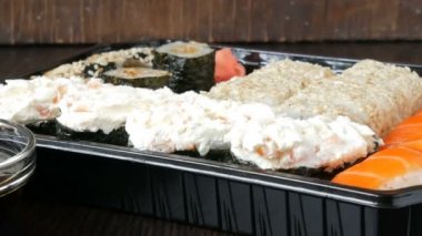 Suşi çeşitli ile ayarla büyük suşi rulo maki, nigiri, şık siyah bir zemin üzerine gunkan yanı sıra. Soya sosu ve ahşap bambu sopalarla yakın.