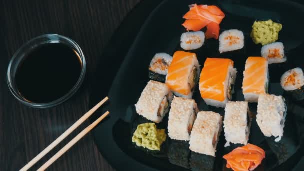 Κομψό μαύρο σούσι σε επίπεδη πλάκα με διαφορετικά είδη ρολό, maki, nigiri, gunkan. Ιαπωνική εθνική κουζίνα — Αρχείο Βίντεο