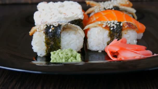 Elegante sushi preto definido em placa plana com diferentes tipos de rolo, nigiri, maki, gunkan. Cozinha nacional japonesa vista de perto — Vídeo de Stock