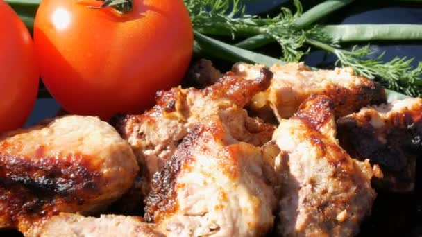 Beautifully decorated dish with pieces of fried steak, tomatoes and greens. Meat barbecue or shish kebab on black dish — Stock Video