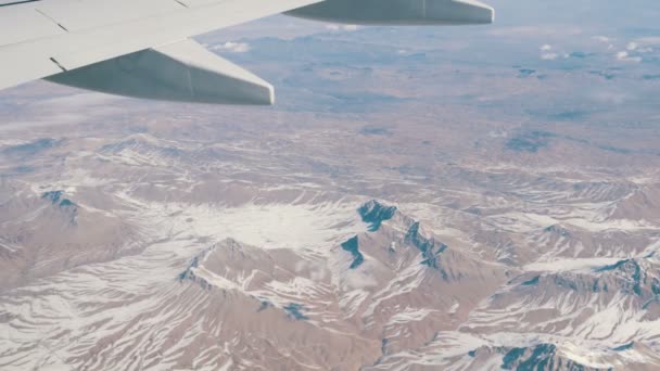 Impresionante belleza de la cordillera, ligeramente cubierta de nieve, pasando por las nubes, una vista desde la ventana del avión — Vídeo de stock