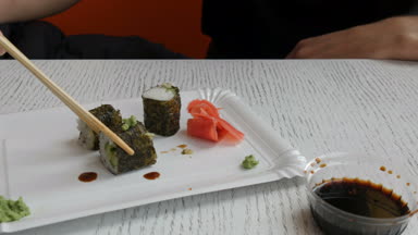 Adam bir Çin bambu çubuk suşi roll alır ve soya sosu dips