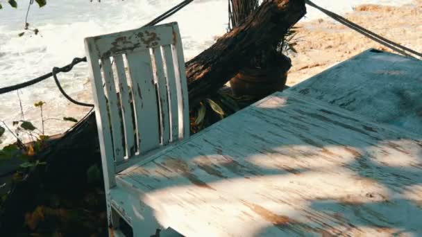 Café abandonado con sillas de madera blanca en la orilla del mar. Mesa de café en la playa — Vídeos de Stock