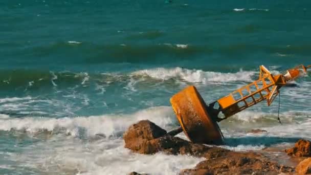 Gran boya amarilla a orillas del mar azul. Las olas golpearon la boya y las grandes rocas en la orilla — Vídeo de stock