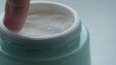 Yeşil kavanoz kozmetik yumuşak krema, krem görünümü kapatın parmak dokunuşları ile. Krem makro parmaklı