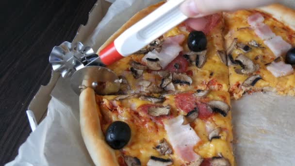 Cuchillo de pizza corta pizza redonda con aceitunas, tocino, salami y queso, vista de cerca — Vídeos de Stock