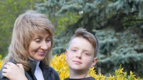 Retrato de una hermosa mujer adulta en años con el pelo blanco y los ojos azules mirando a su hijo adolescente y sonriendo suavemente con ternura. Día de las Madres — Vídeos de Stock