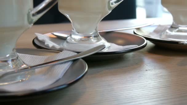 Un número de vasos con café con leche de pie en un platillo sobre una mesa en un café — Vídeos de Stock