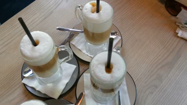 Hermosos vasos con café con leche y espuma grande en el café en la vista superior de la mesa — Vídeo de stock