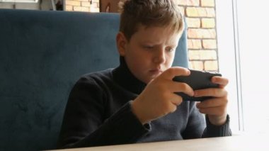 Çocuk genç siyah smartphone bir oyun oynuyor