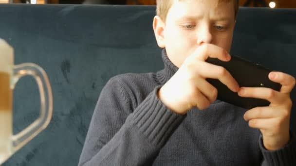 Хлопчик підліток грає в гру на чорному смартфоні — стокове відео