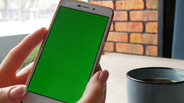 Smartphone tela verde. Chroma Key em um smartphone branco, as mãos femininas seguram o telefone celular em um café — Vídeo de Stock