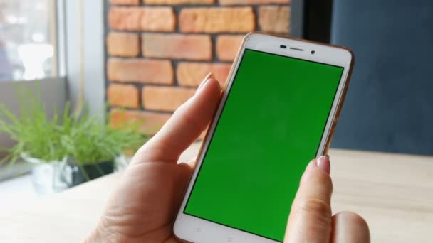 Зеленый экран смартфона. Ключ от Chroma на белом смартфоне, женские руки держат мобильный телефон в кафе — стоковое видео