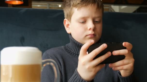 Niño adolescente jugando un juego en el teléfono inteligente negro — Vídeo de stock