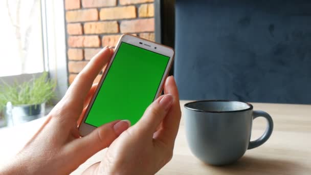 Zielony ekran smartfona. Chroma Key na biały smartphone, kobiece ręce trzymać telefon komórkowy w kawiarni obok filiżankę kawy — Wideo stockowe