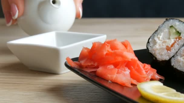 Mani da donna ben curate con una bella manicure versano salsa di soia da una mini teiera in casseruola, accanto alla tavola del sushi — Video Stock