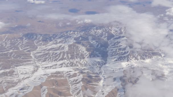 Splendida bellezza della catena montuosa, leggermente coperta di neve, passando dalle nuvole, una vista dal finestrino dell'aereo — Video Stock