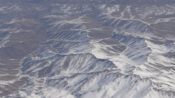 Beleza deslumbrante da cordilheira, ligeiramente coberta de neve, passando por nuvens, uma vista da janela do avião — Vídeo de Stock