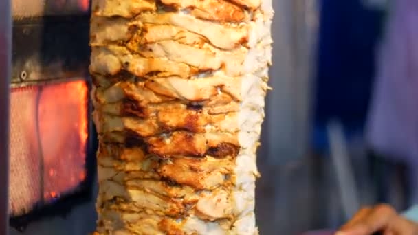 Un hombre con un cuchillo cortó carne para shawarma o Denner en un pincho especial, vista de cerca. Mercado nocturno, Pattaya, Jomtien. Cocina tailandesa. Asiáticos exóticos platos en el mercado — Vídeo de stock